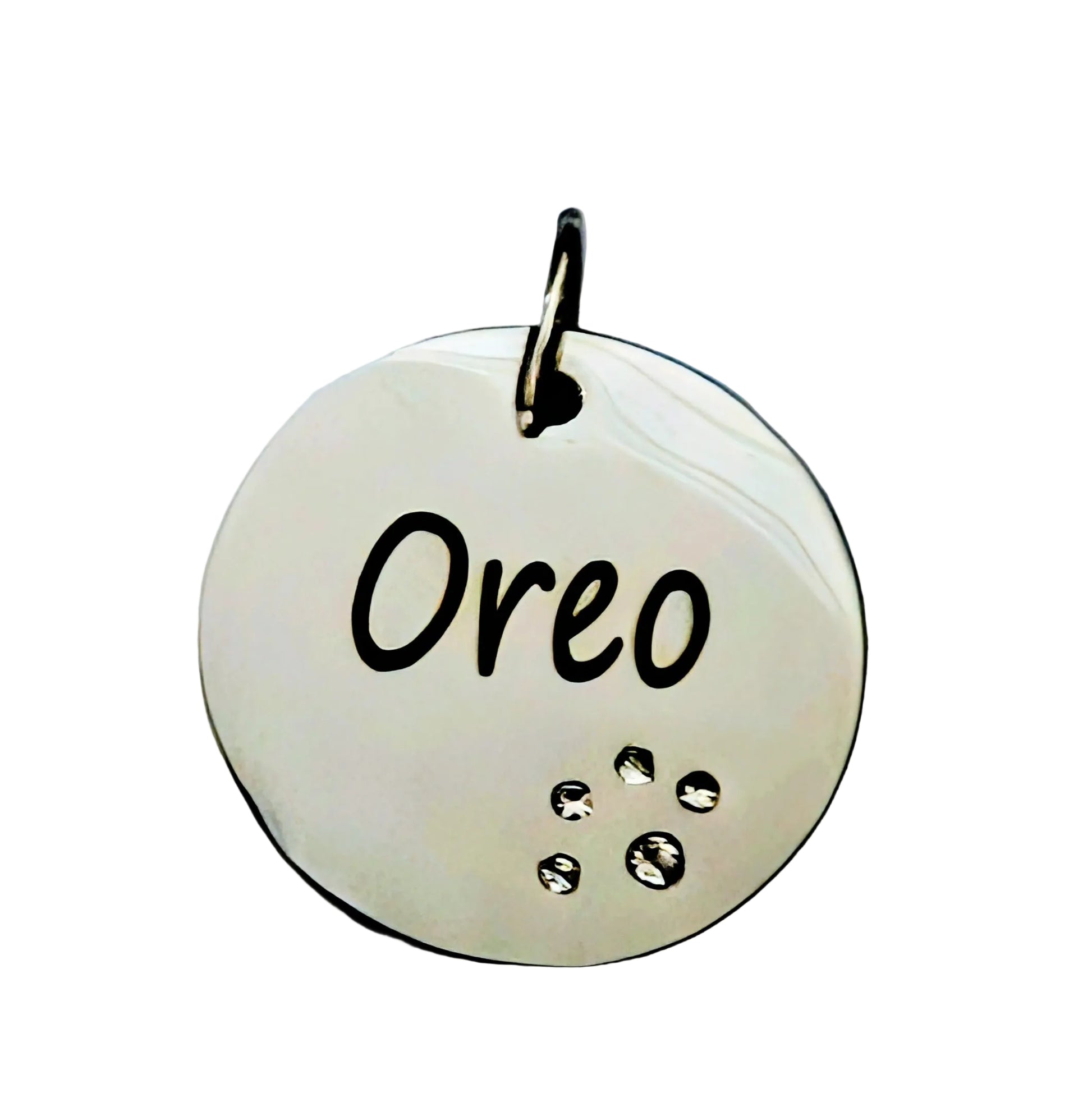 Silver pet tag with 'Oreo' engraved on a light gray background